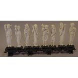 Eight carved ivory figures on carved wooden stand 31 cm long, 14 cm high approx.