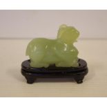 Oriental carved green stone figurine on timber base, 6.5cm wide
