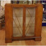 Art deco maple display cabinet with geometric glass panel doors opening to inside glass shelves,