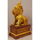 Large Chinese carved gilt temple lion statue on stand, H74cm approx