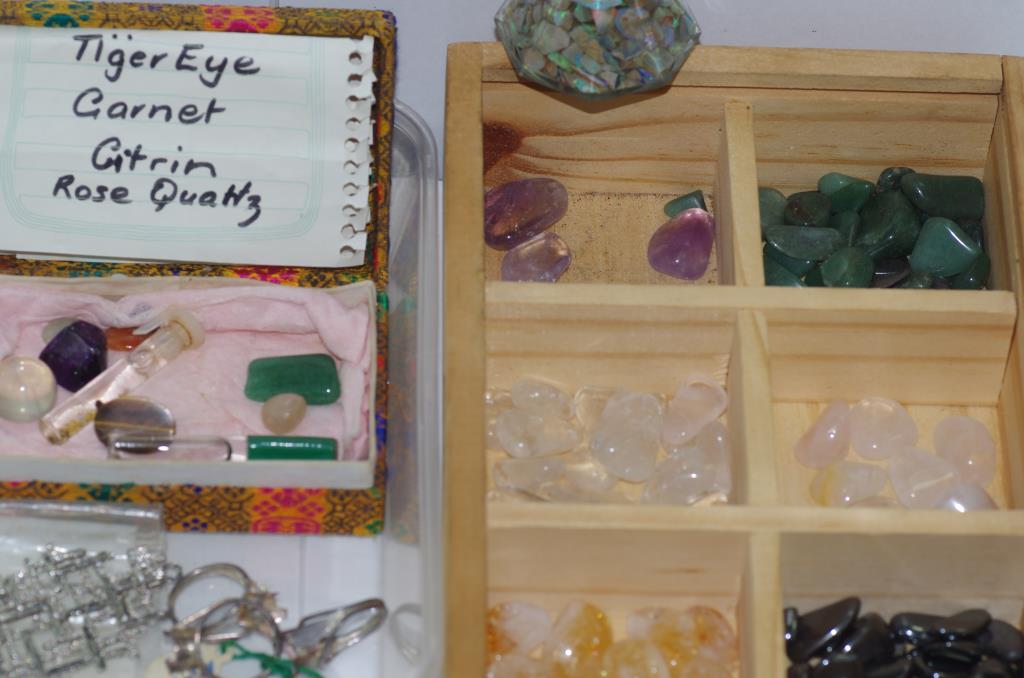 Various unset gemstones including opal jade, tigers eye etc and some gold flakes together with a box