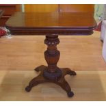 Mahogany pedestal card table with fold over swivel top supported by a turned carved column on