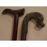 Two carved timber walking sticks to include one with a dragon head handle and the other a mythical