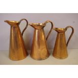 Three graduated copper jugs 26cm high (tallest)