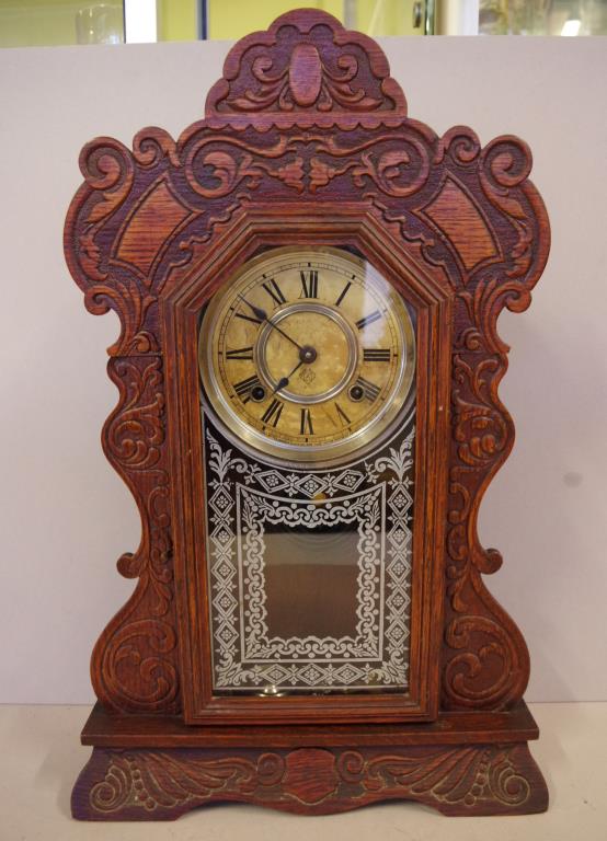 Antique Ansonia cottage clock with eight day striking movement, in ornate oak case, key and pendulum