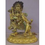 Tibetan gilt metal Yama figure astride a buffalo crushing a prostate figure, his consort Chamundi,