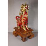 Oriental carved wooden temple lion on rectangular wooden stand, 41cm high (total)