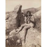 Gloeden, Wilhelm von: Young boy on a rock playing the flute Young boy seated on rock playing the