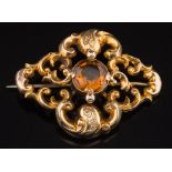 A Victorian gold and citrine mounted single stone brooch: of scroll work design with central,