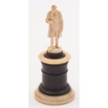 A small Dieppe ivory figure of Napoleon: wearing a long tail coat, one hand inside his waistcoat,