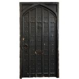 A Gothic pointed arch and black painted and iron studded panelled door:, in a softwood frame,