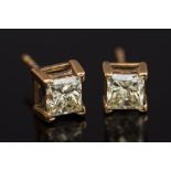 A pair of princess-cut diamond single stone ear studs: each set with a single princess-cut diamond