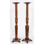 A pair of carved satinwood and decorated torchere stands:, with circular moulded tops on reeded,