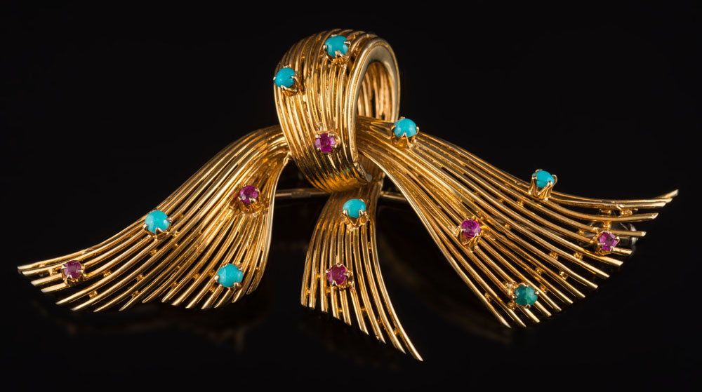A turquoise and ruby mounted stylized bow brooch: highlighted with circular turquoise and rubies, 7.
