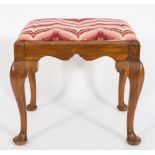 A walnut stool of George I design:, with an upholstered needlework slip in seat and shaped apron,