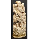 A Japanese carved and stained ivory okimono of Jurojin: the smiling god seated on a deer and