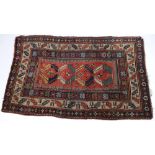 A Kazak rug:, the brick red field with four serrated diagonal geometric medallions,