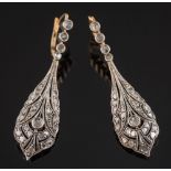 A pair of diamond mounted pendant drop earrings: each with a pierced tear-drop millegrain-set with