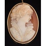 An oval shell cameo portrait brooch: depicting a classical woman, her hair adorned with curls,