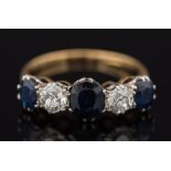 A gold, sapphire and diamond five stone ring: with graduated, oval sapphires between round,