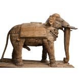 A large stripped wood Indian elephant: dressed in ceremonial hangings, with drapes and bosses,