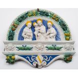 An Italian 'Della Robbia' maiolica plaque: of arched form,