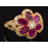 A modern ruby and diamond flower head cluster ring: with six petals each inset with an oval ruby,