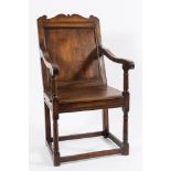 An early 18th Century oak open armchair:, the moulded panel back with shaped fret cut cresting,