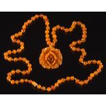 An amber bead single-string necklace: suspending an amber coloured carved flower pendant,