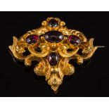 A mid 19th century gold and garnet brooch: of openwork foliate scroll design with five oval