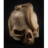 A Japanese carved bone okimono of a serpent emerging from a skull: the serpent eyes stained black,