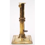 An early 18th century brass ejector candlestick: the plain nozzle and stem with hooked lip and