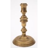 A late 17th century brass candlestick: with urn shaped nozzle on a knopped stem,