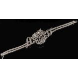 A diamond mounted bracelet: of stylised ribbon design with a central informal cluster of round,