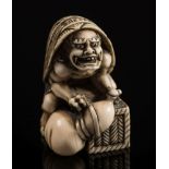 A Japanese carved ivory okimono: depicting an oni with a turtleshell on it's back and squatting on