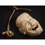 A Japanese carved ivory miniature mask: of a laughing man with open mouth and only two teeth,