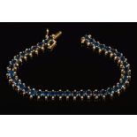 A sapphire and diamond line bracelet: with 40 oval sapphires each approximately 4.2mm long, 17.
