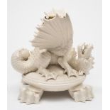 A Belleek porcelain dragon kettle stand: modelled as a dragon with wings outstretched and head