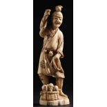 A Japanese carved ivory okimono: of a peasant holding a rope, with a basket of fruit at his feet,