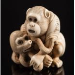 A Japanese carved ivory netsuke, depicting a monkey holding a young octopus: both with inset eyes,