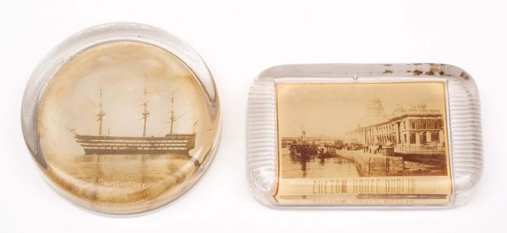 A circular glass paper weight with sepia print of HMS Victory: and a similar rectangular weight