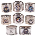A collection of seven silver plated and enamel shipping line napkin rings together with a plain