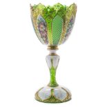 A Bohemian green and white overlay glass pedestal vase: of foliate form on a domed foot,