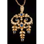 An Edwardian 15ct gold sapphire and seed pearl pendant: of open work scroll design suspending three