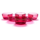 A set of six cranberry glass finger bowls: of circular form with star cut bases and gilt rims,