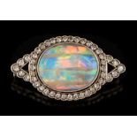 A black opal and diamond mounted oval brooch: the central oval black opal 19mm x 15mm,