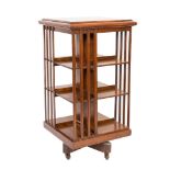 An Edwardian oak square revolving bookcase:, with a moulded top and slatted uprights,