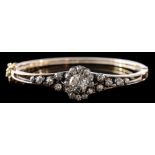 A late 19th century gold, silver and diamond mounted hinged bangle: with central oval cluster,