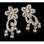 A pair of diamond mounted floral cluster pendant earrings: each with a five petal cluster