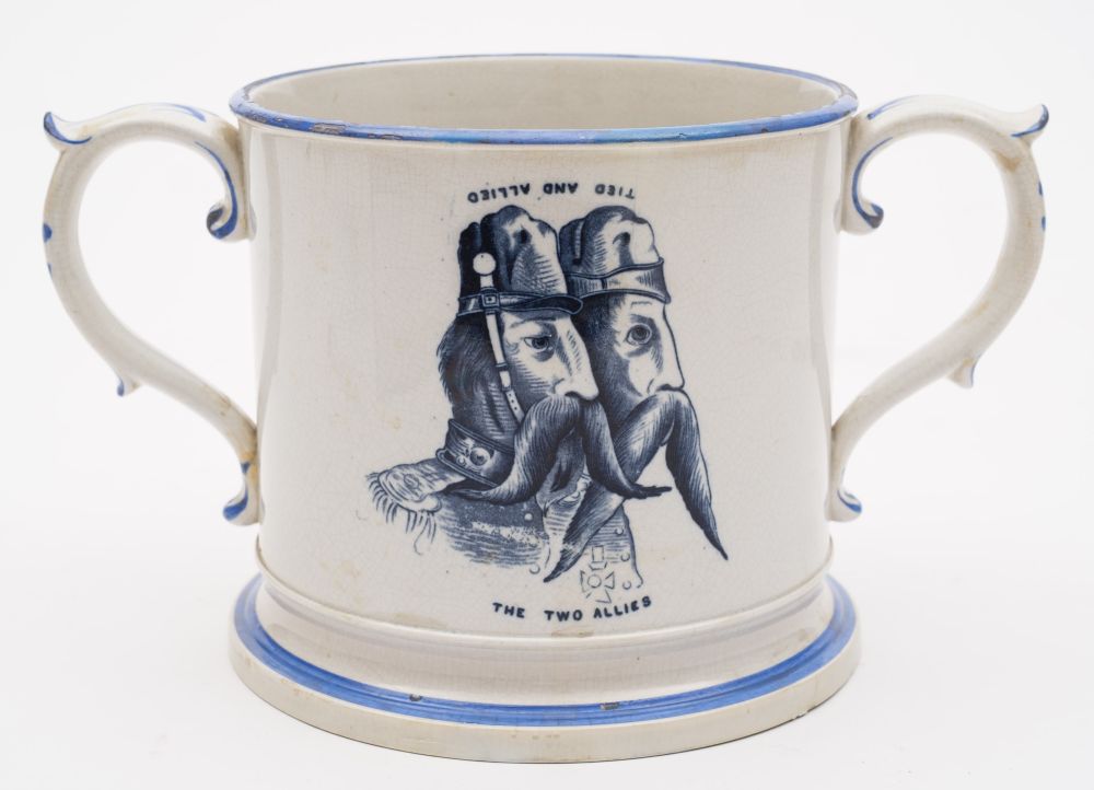 A pottery commemorative loving cup: printed in dark blue with a pair of mustachioed soldiers above